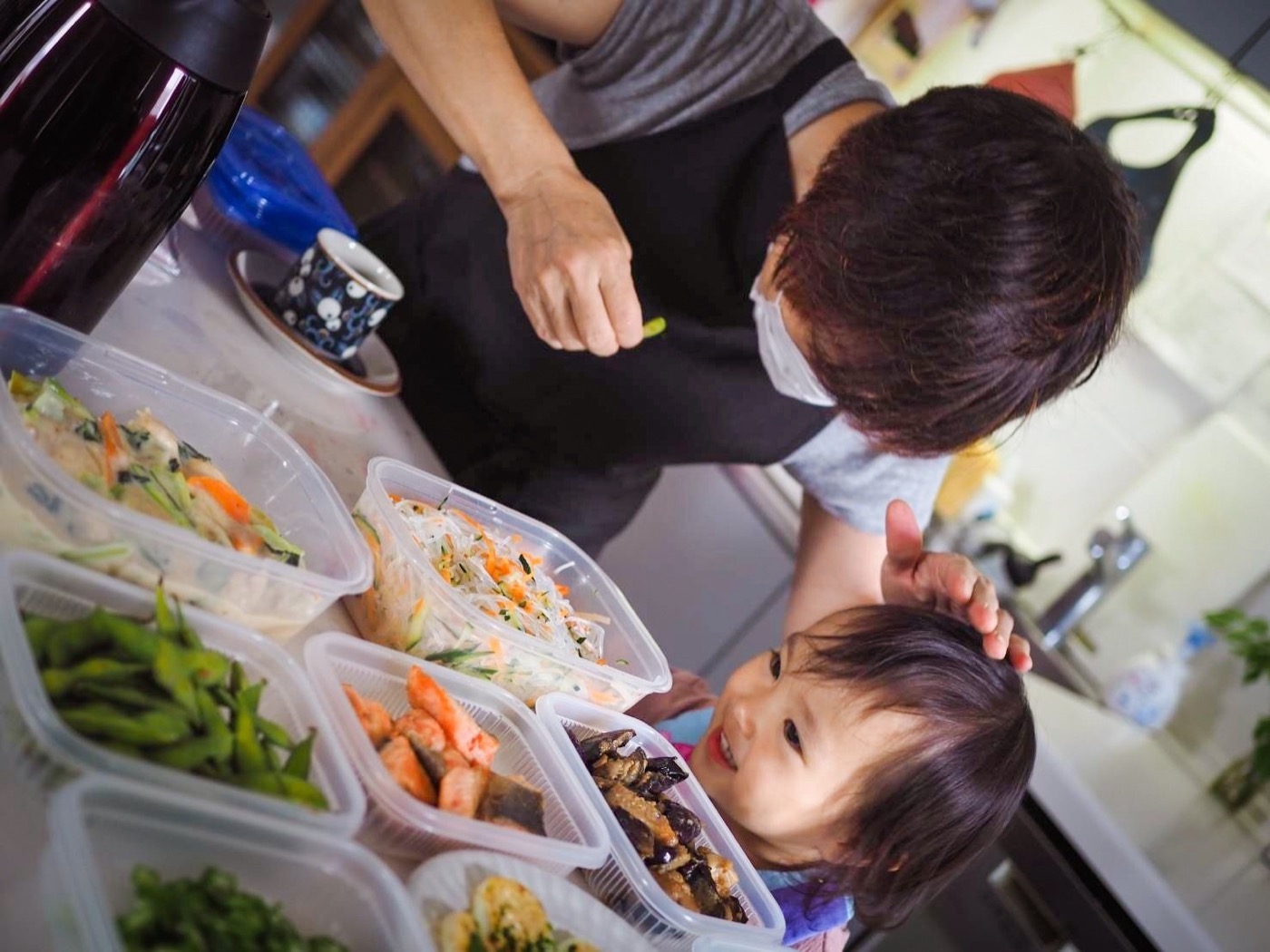 作り置きの料理を前に、サポーターとお子さんが笑顔で向き合っている様子